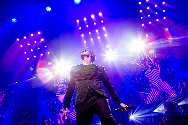 Lead singer performing on stage with lighting